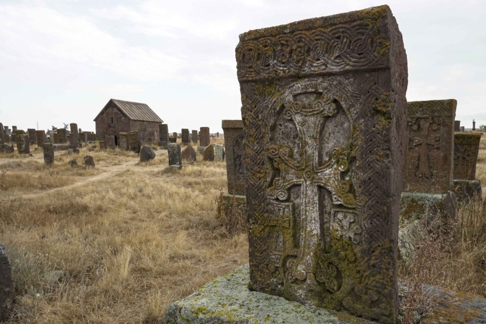 Campo di khachkar nel cimitero di Noratus, vicino al lago Sevan in Armenia, con croci di pietra scolpite e montagne sullo sfondo